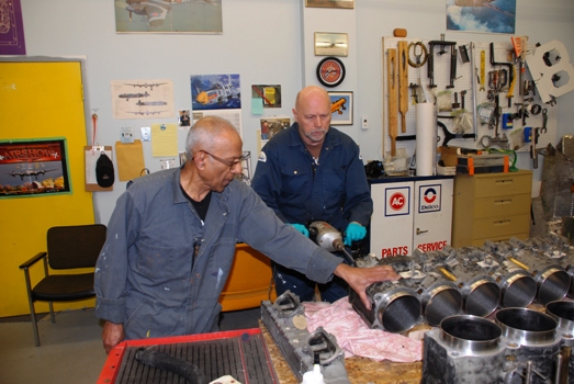 Roberto Fernandez supervises Andy Woerle who is honing the cylinders of the Hurricane's Merlin engine.