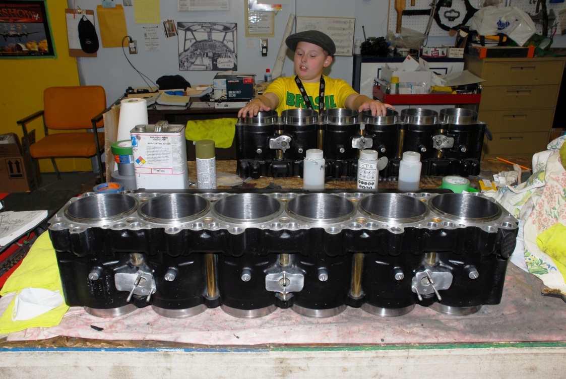 CMS's youngest volunteer Jordan admires some of his handiwork on the newly primed and painted Merlin engine cylinder banks.